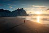 A man walking along the beach with Vestrahorn mountain in summer at Iceland