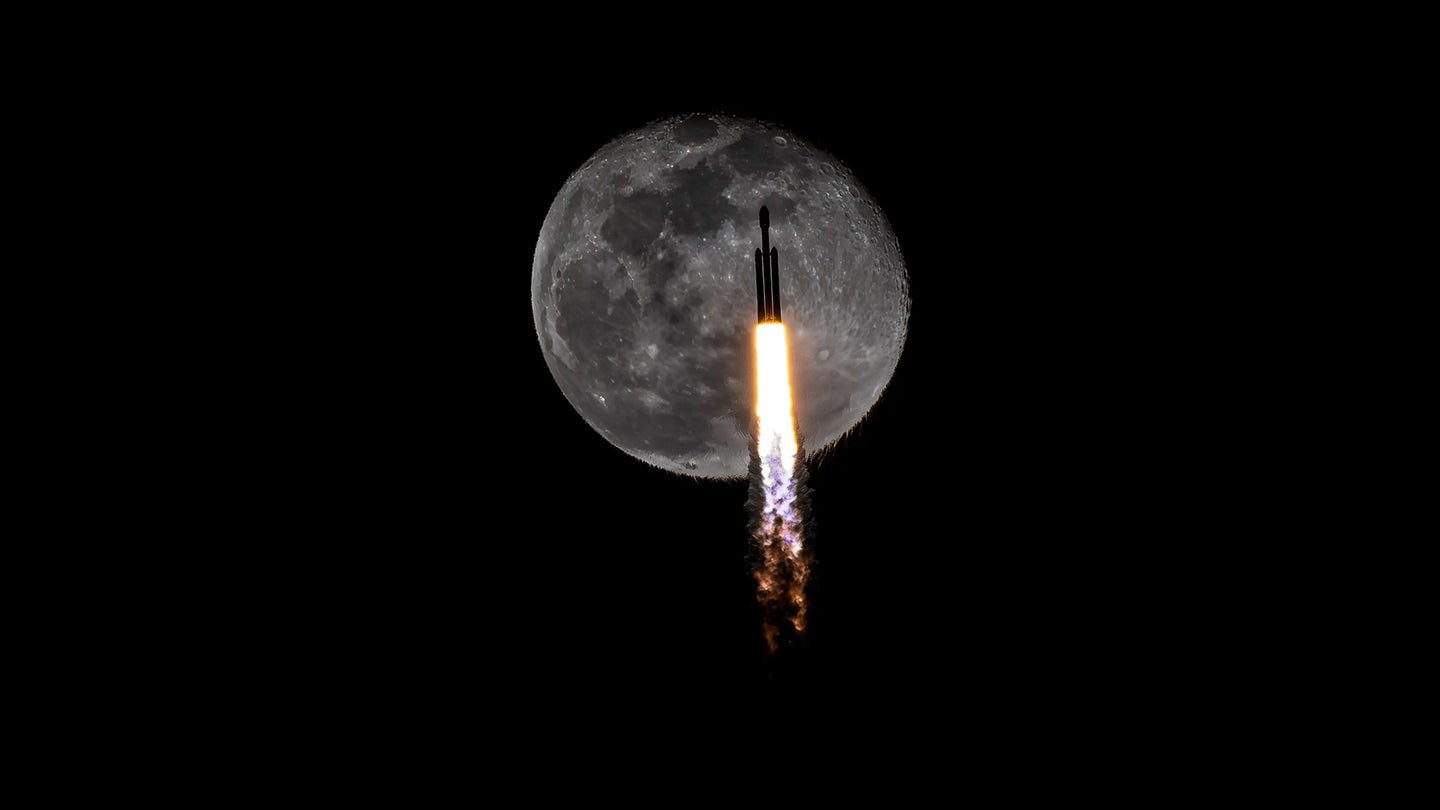 A silhouette of a rocket passes in front of the moon