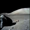a robotic vehicle sits next to a boulder on the grey sands of the moon
