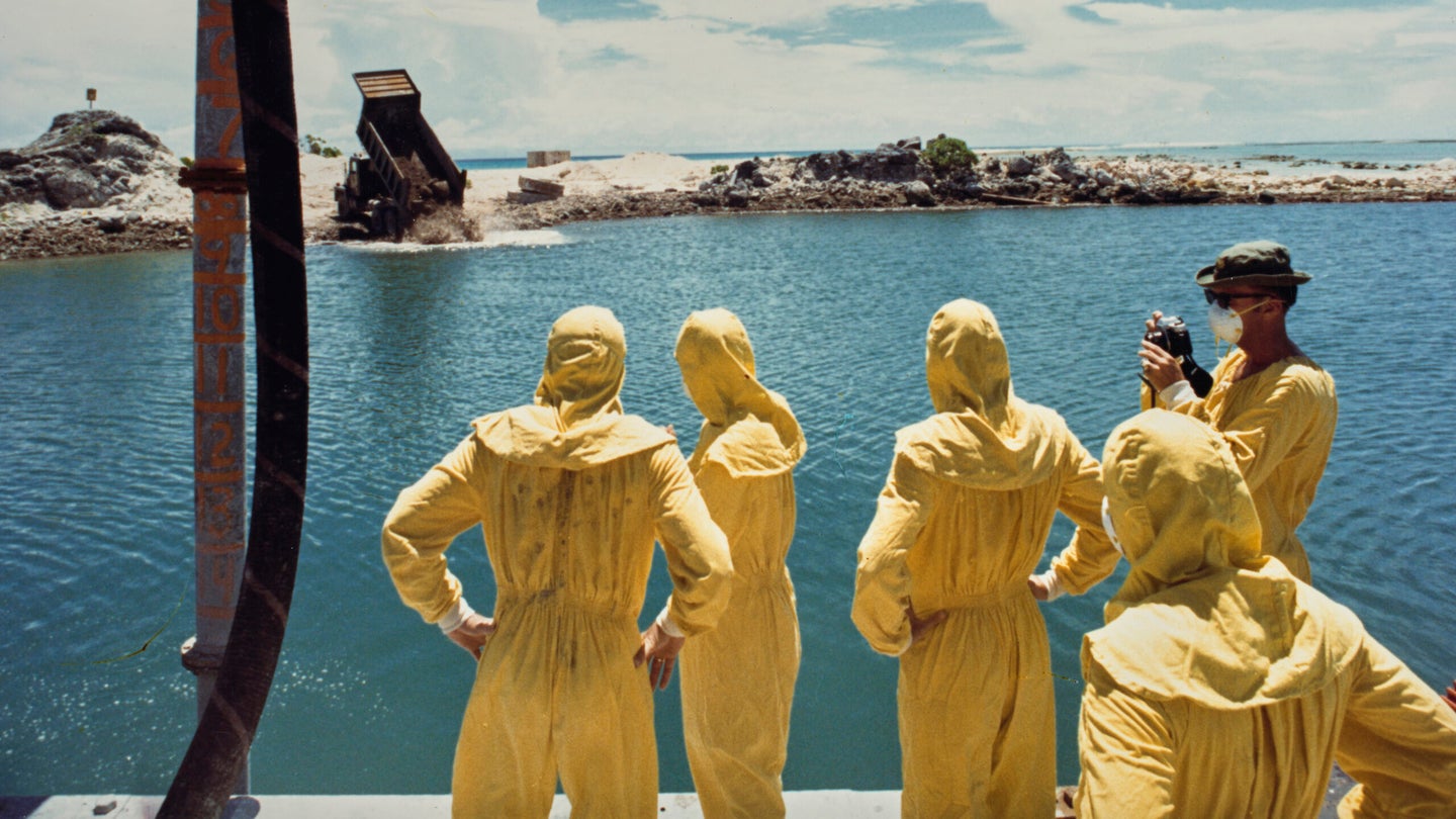 U.S. military officers watch nuclear waste being dumped on Runit Island in the Marshall Islands.