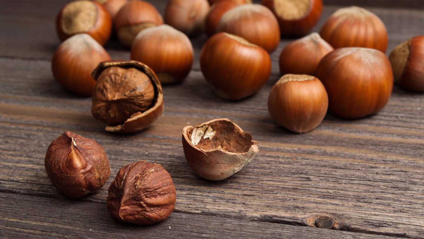 Shelled and unshelled hazlenuts on a wooden table.