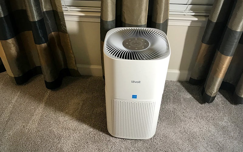 White round Levoit Core 600S air purifier on carpet in front of curtains