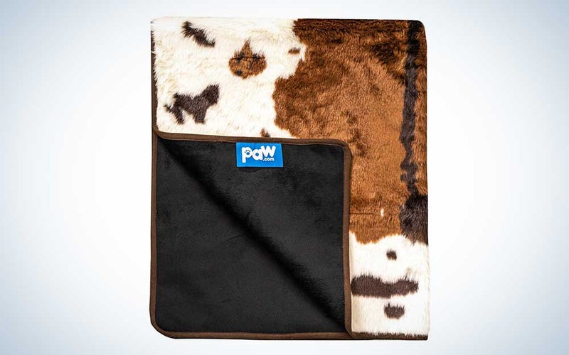 A brown and white PupProtector cowprint dog blanket on a plain background