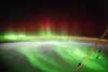 a green aurora with the 'legs' of the international space station 