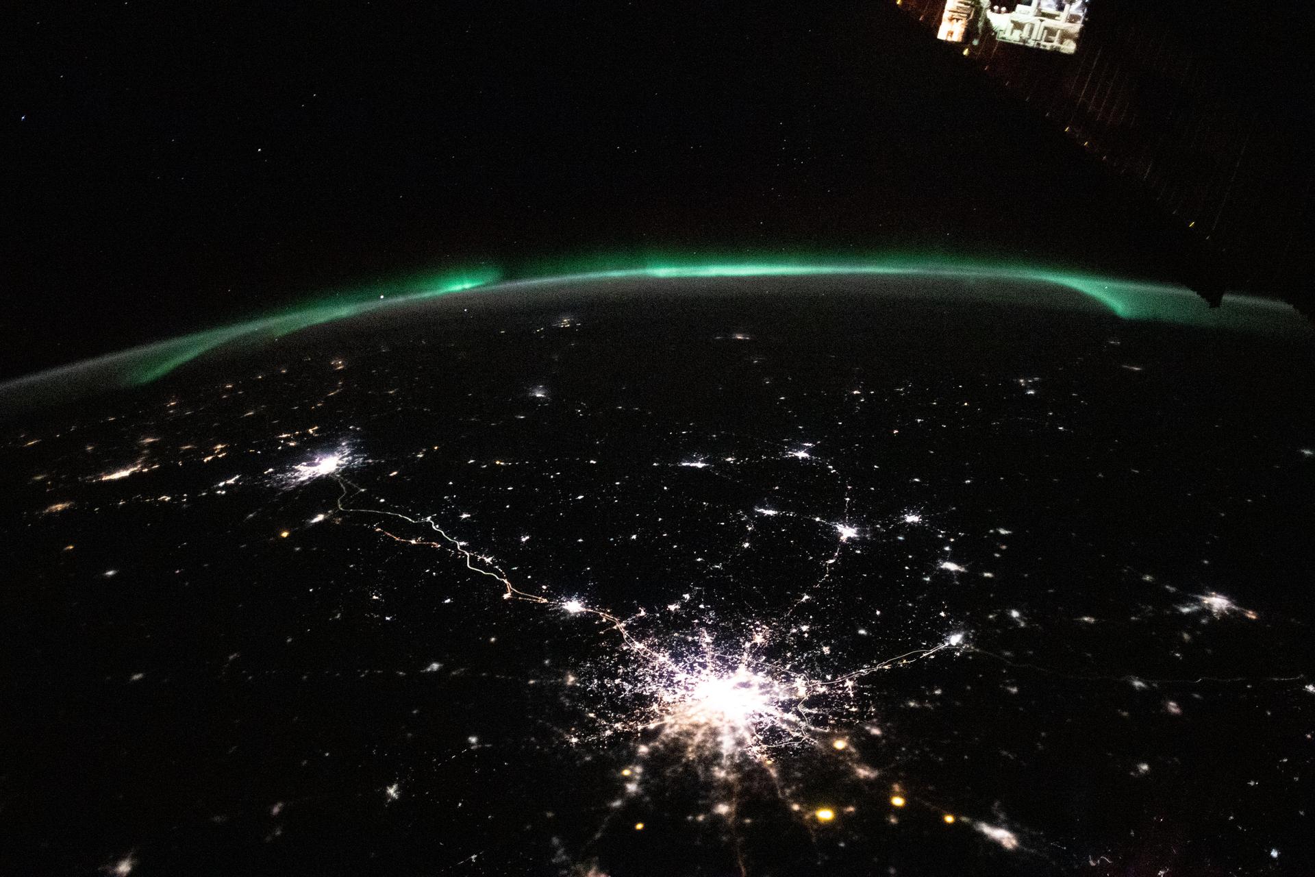 city lights in the night's sky with a green aurora overhead
