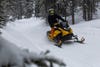 a snowmobile rides a yellow snowmobile in the woods