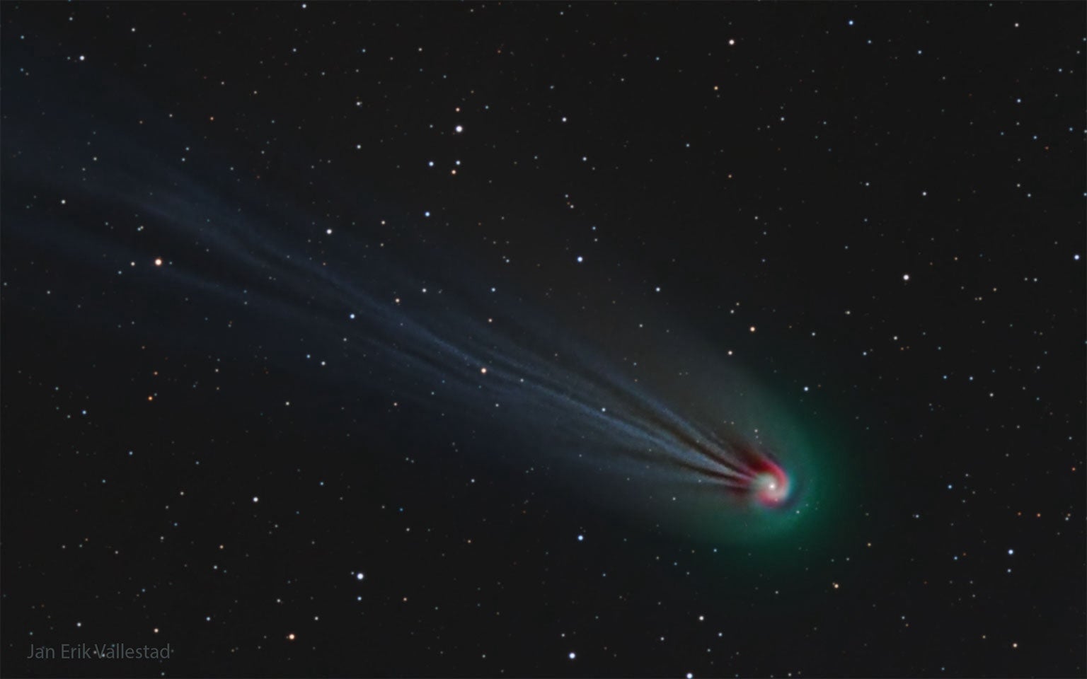 Comet 12P/Pons-Brooks in the night sky. Green glowing gas swirls around a white center and red glowing gas encircles the green.