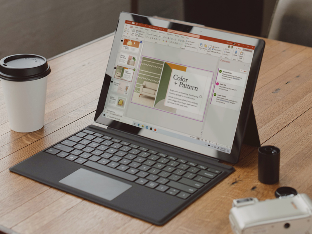 A Microsoft Surface laptop sitting on a desk with Microsoft Powerpoint pulled up.
