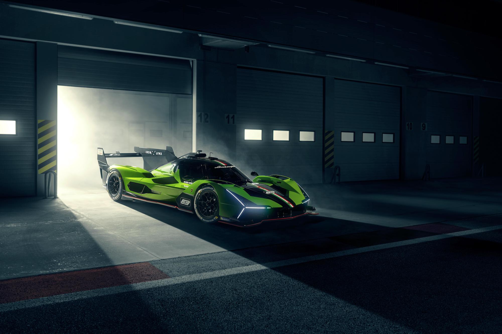 a green race car emerges from a garage on a dark night 