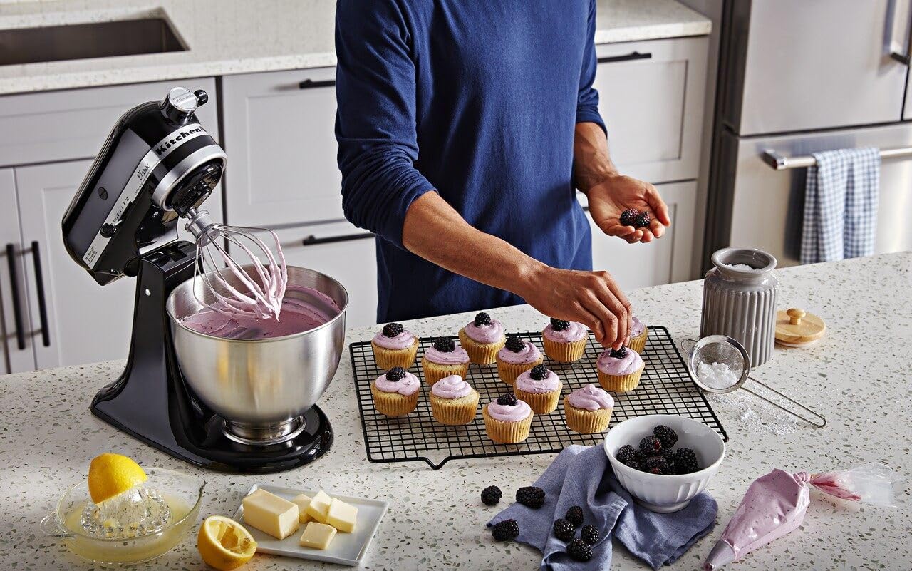 A person making black raspberry cupcakes using a KitchenAid stand mixer.