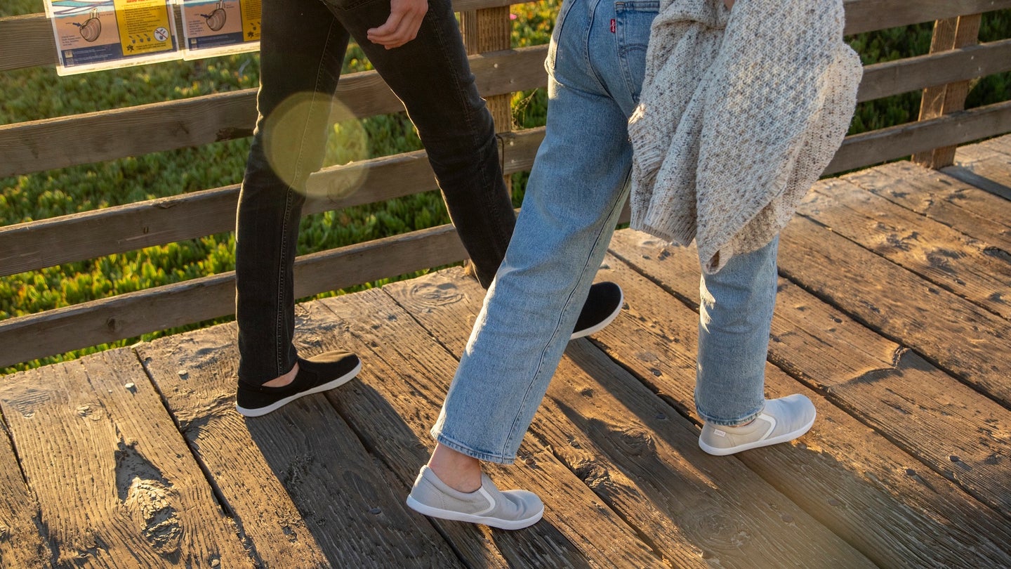 two sets of legs walking on a wooden boardwalk