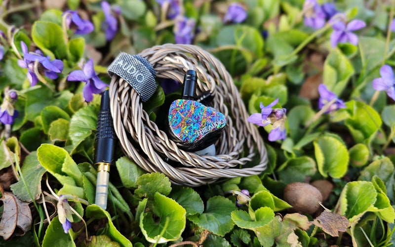 Thieaudio Monarch earbuds by some flowers.