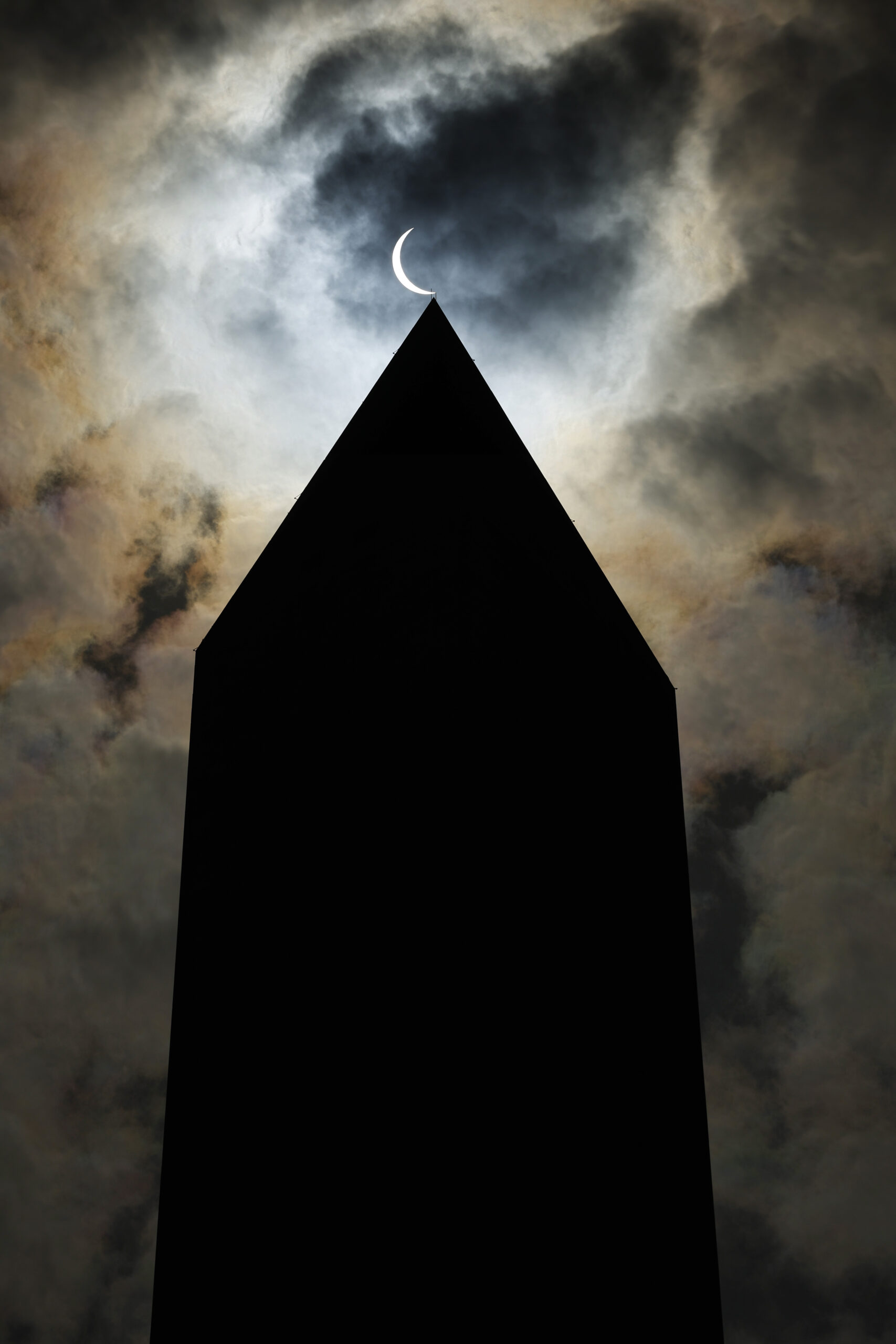 a partial sliver of the sun seen above the washington monument
