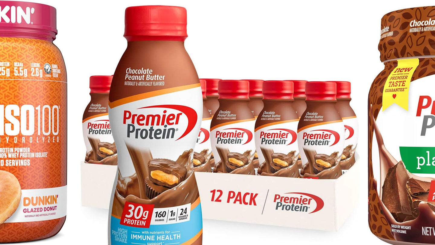 A case of Premier Protein shakes on a plain bacckground with other protein powders next to it