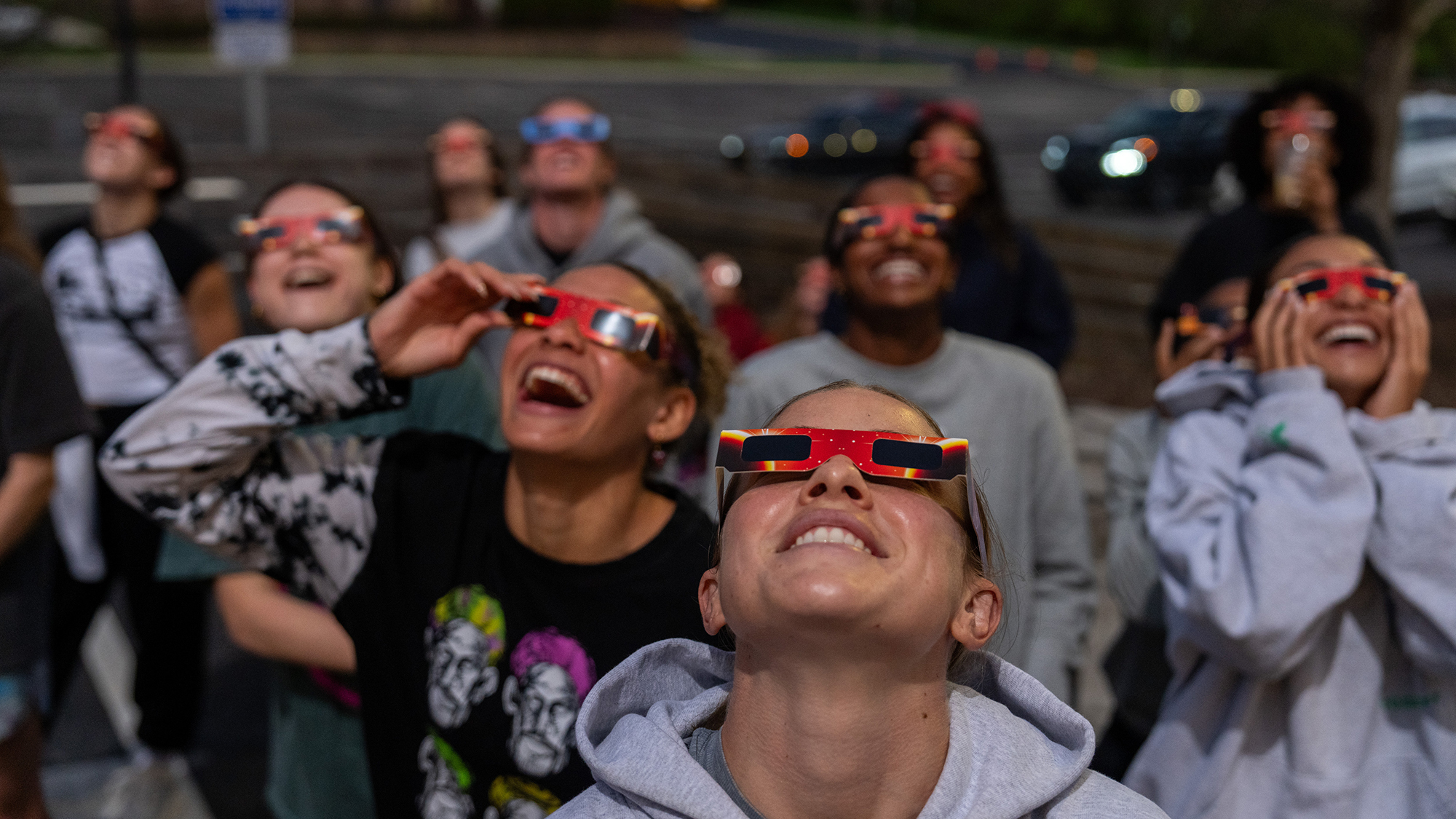 People looking up at eclipse wearing protective glasses