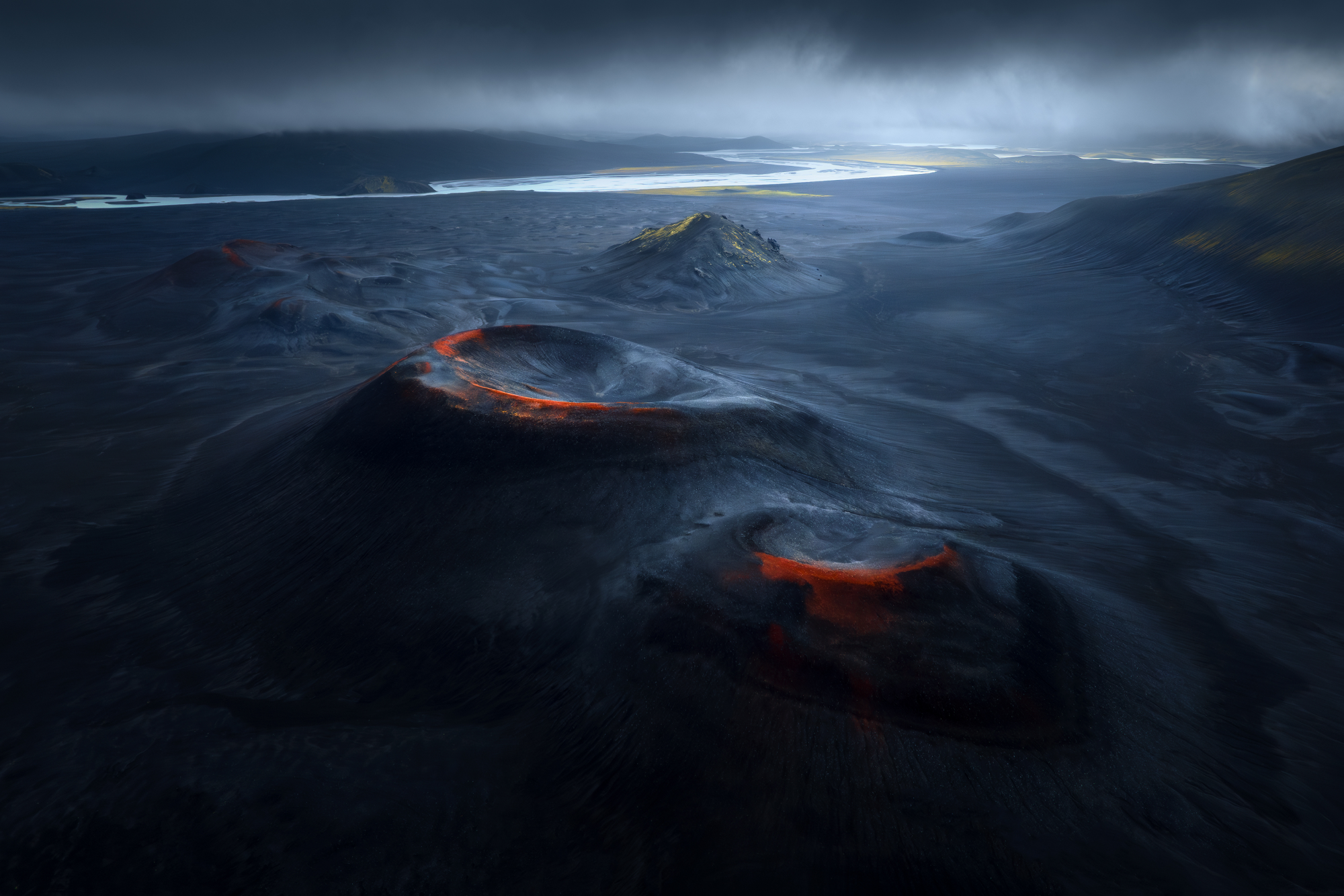 red and black volcanic craters form circular shapes in black sand 