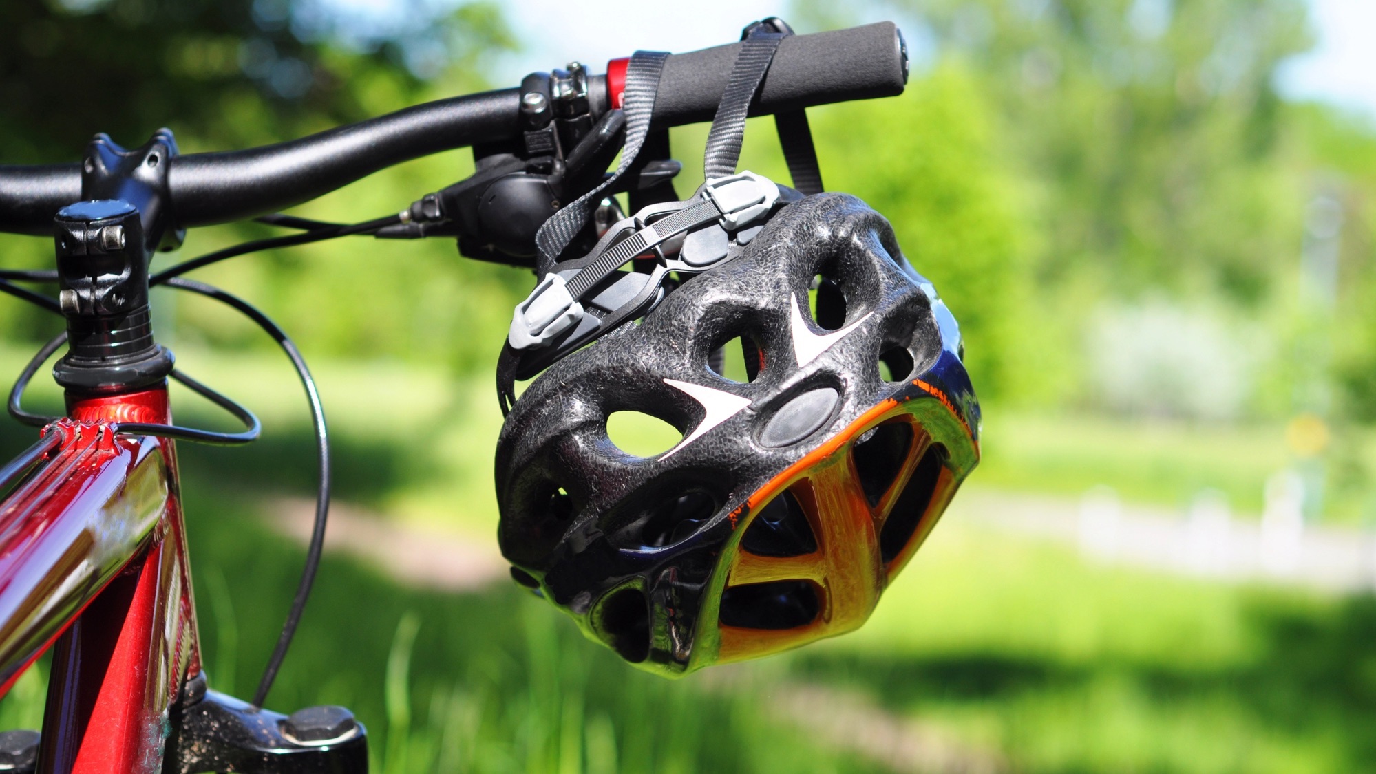 a black bike helmet dangles from the handlebars of a bicycle