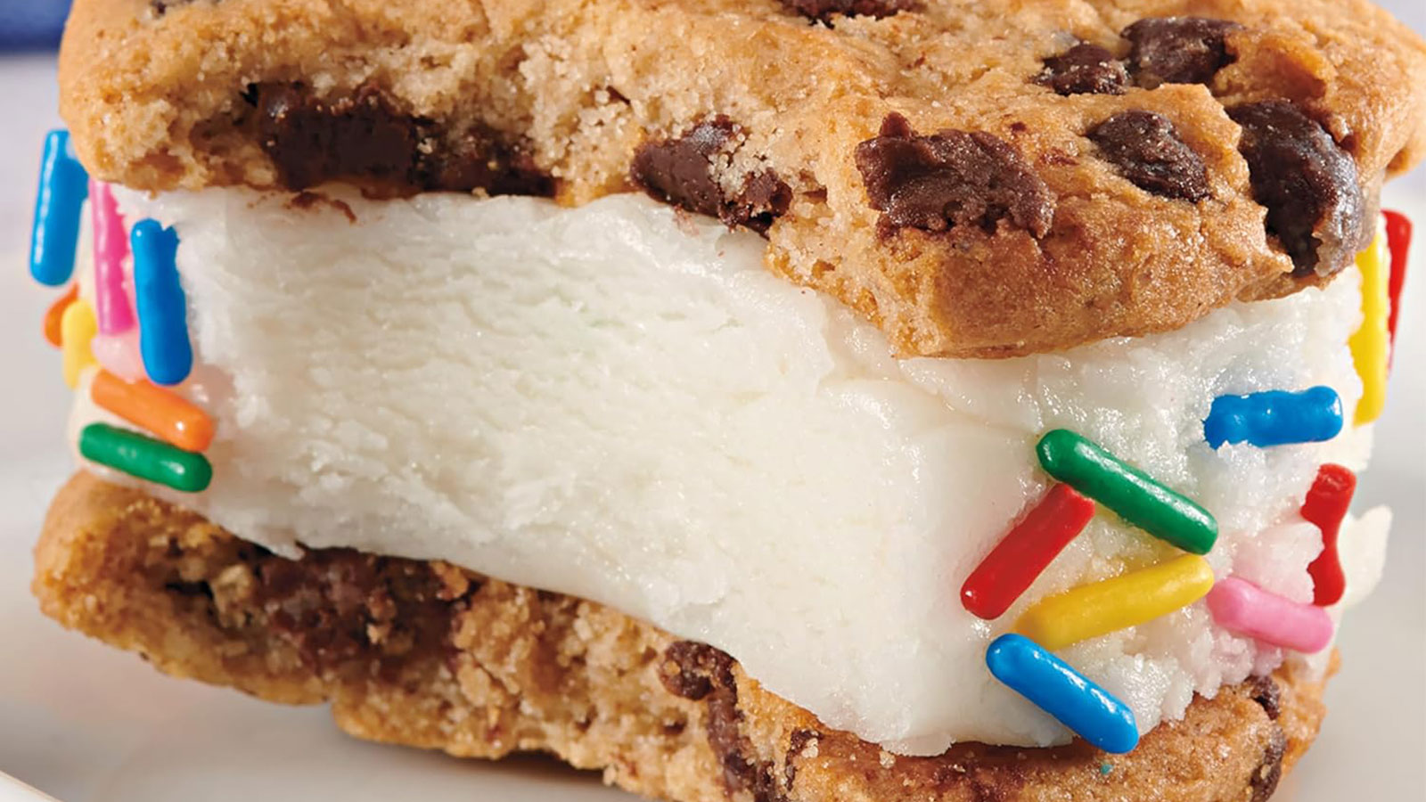 An ice cream sandwich made between two cookies with sprinkles on the outside close-up