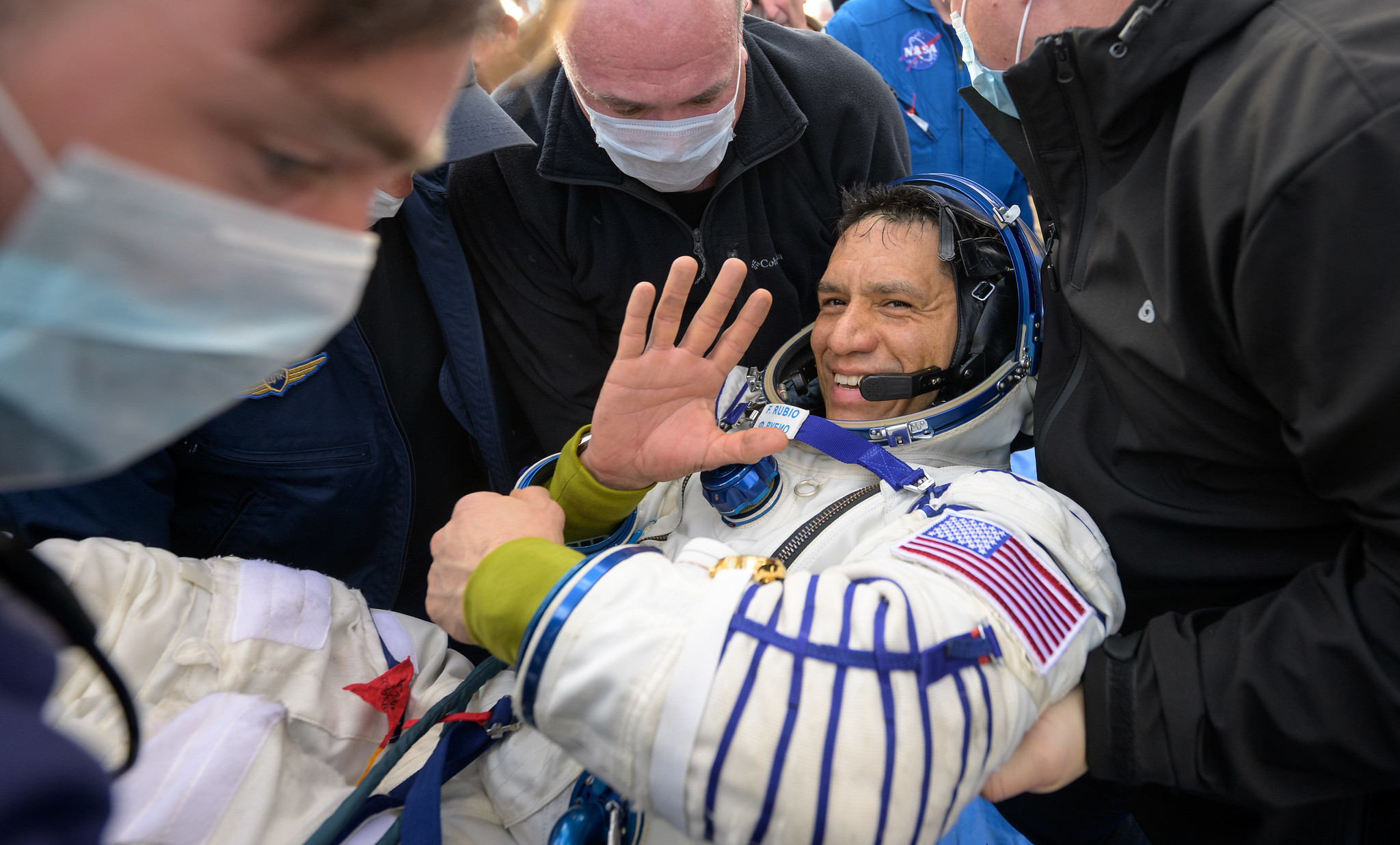 a man in a space suit waves at the camera