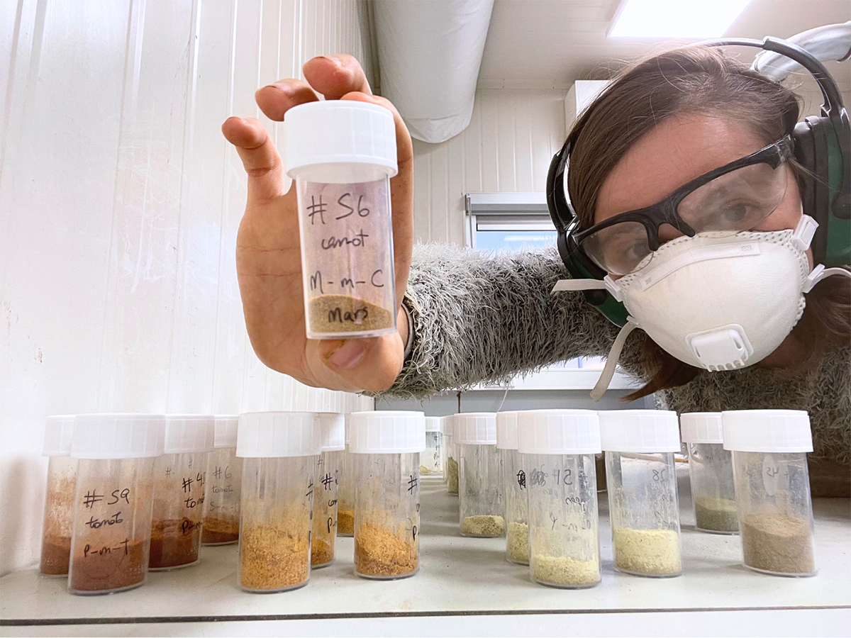 a scientist holds dried samples from harvested plants in clear containers