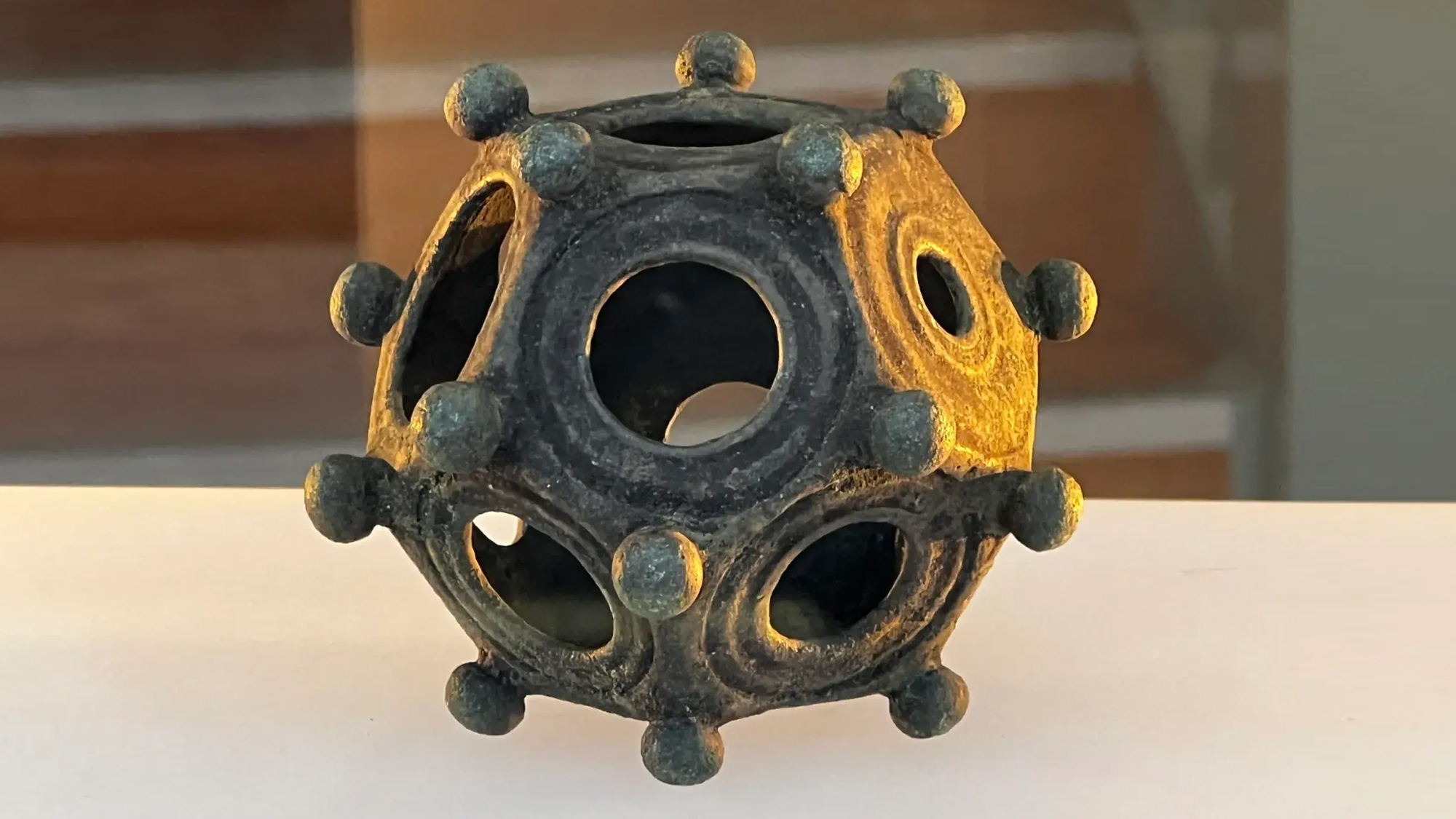 a hollow 12-sided object with knobs on each face on display at a musuem.