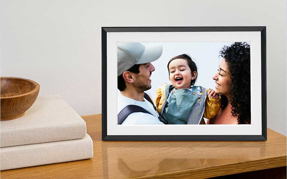 An Aura Carver frame on a table displaying a photo of a family.