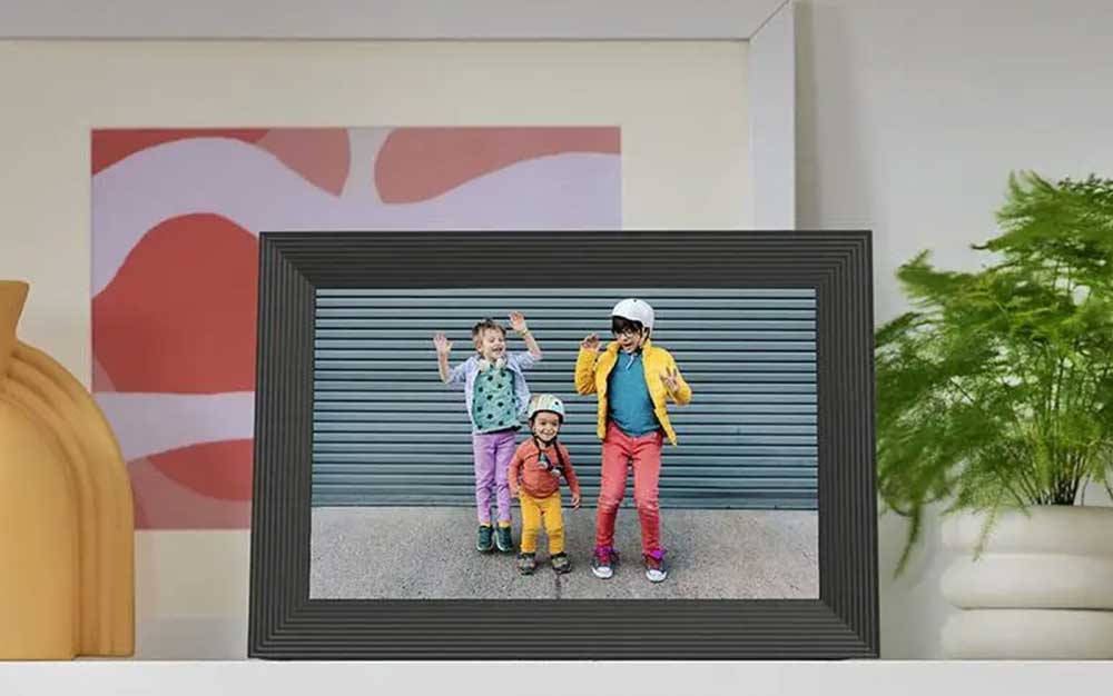 An Aura Carver frame displayed on a mantle showing a picture of a family together.