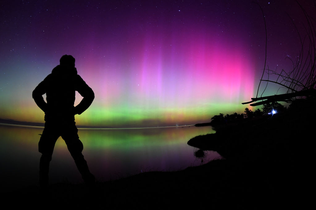 silhouette of a person standing in front of aurora lights