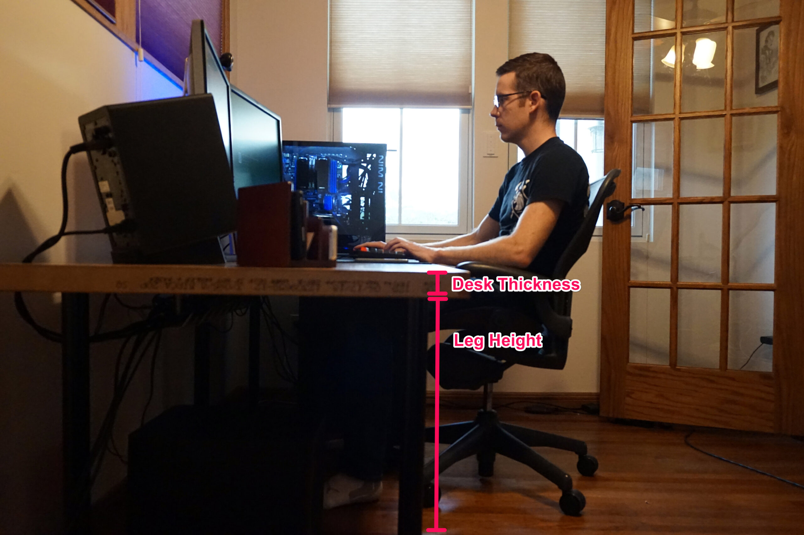 A man sitting at a DIY computer desk, with a small diagram showing how to visualize the desk thickness and height for better ergonomics.