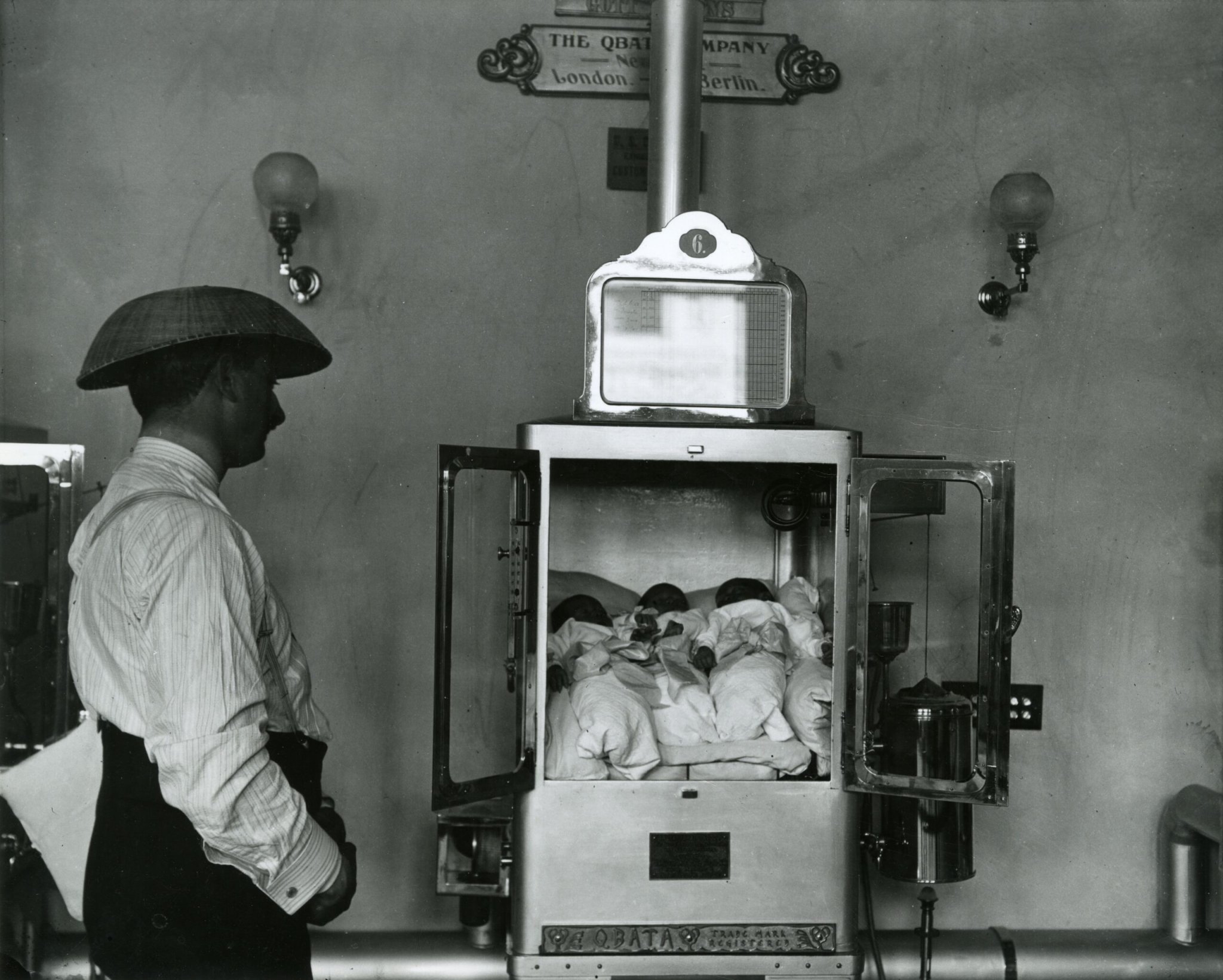 a man looks at several babies in an incubator 