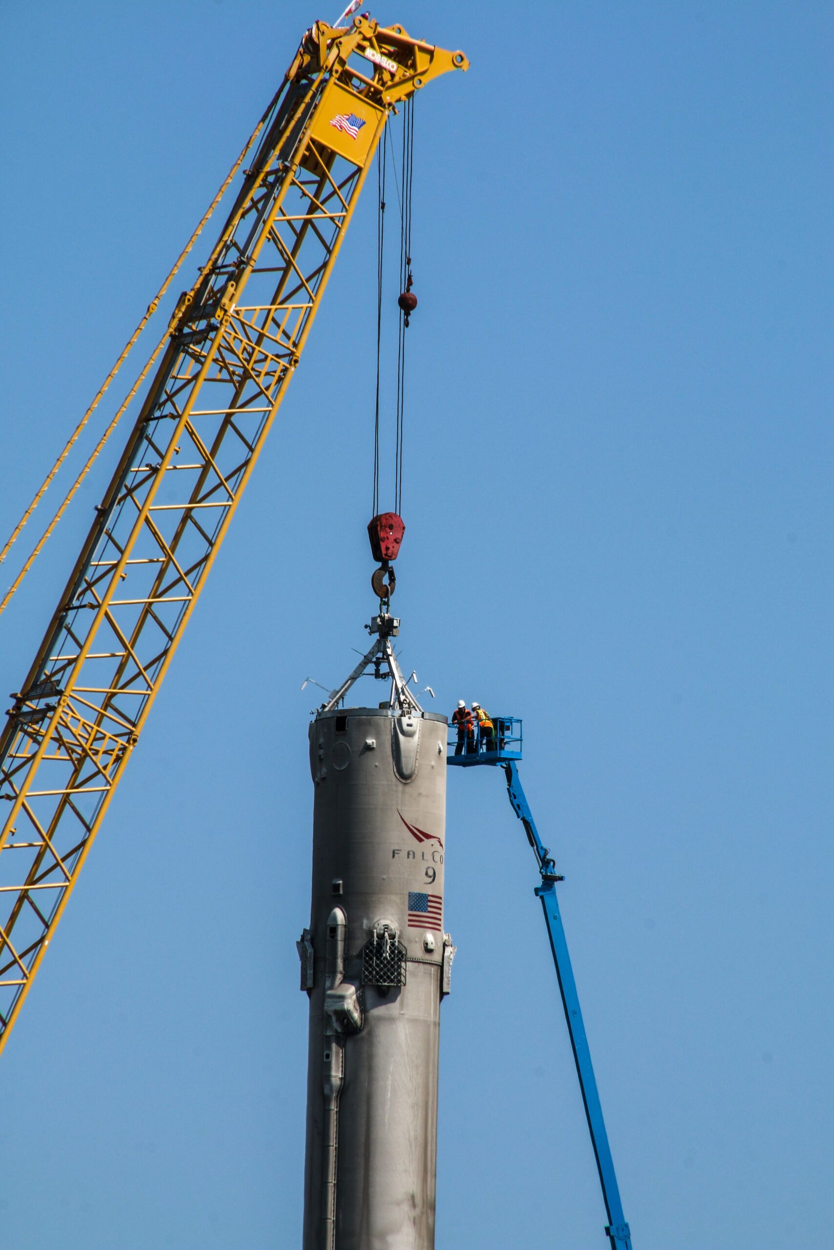 workers attach a cable to the Falcon 9