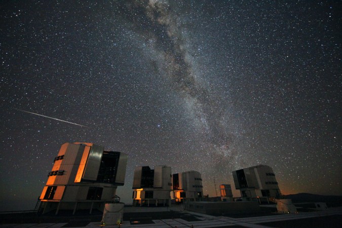 starry night sky above telescopes on hill 