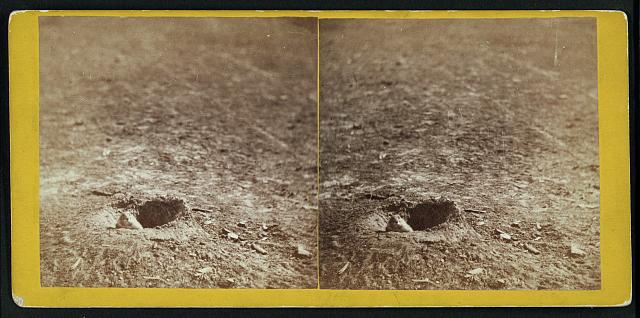 two holes in the ground with prairie dogs peeking out