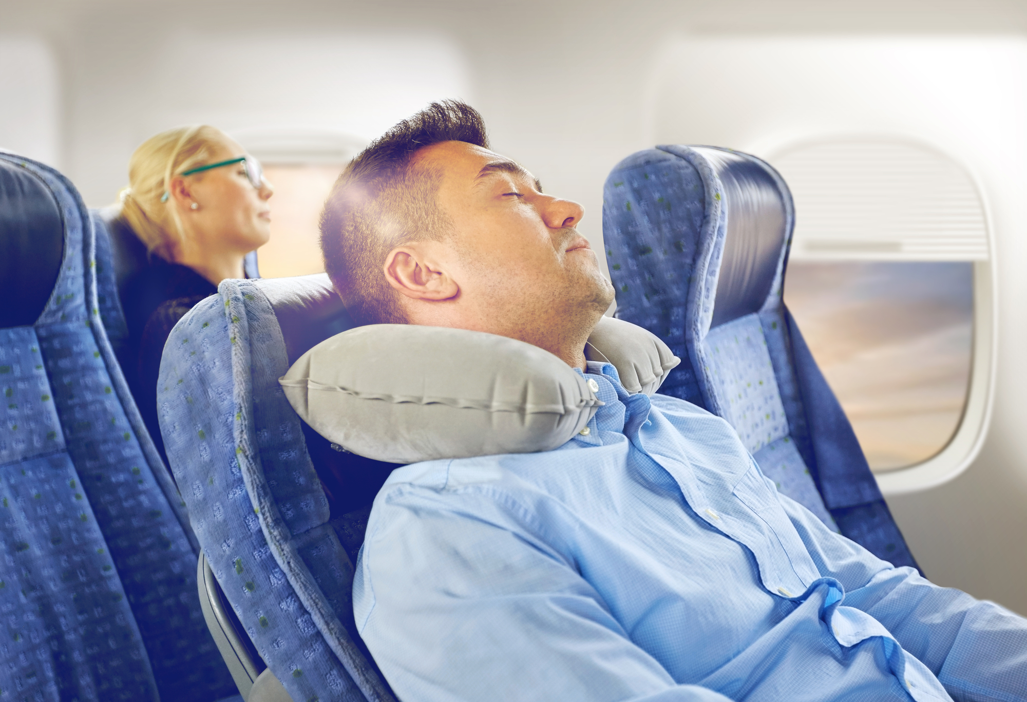 Person sleeping in plane with cervical neck pillow
