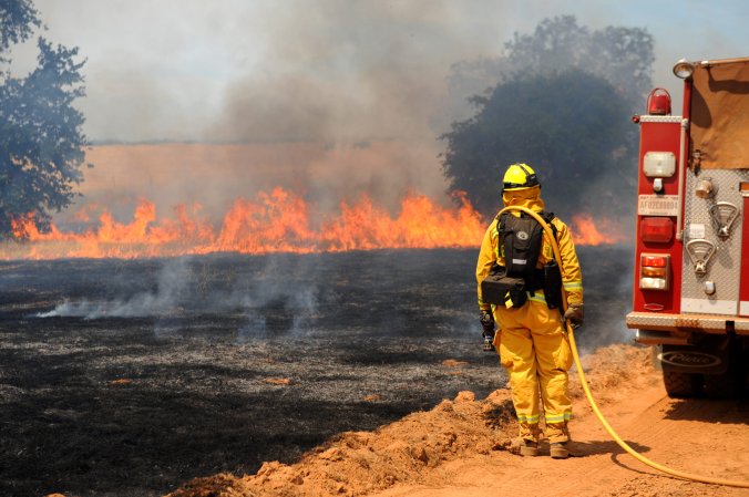firefighter looks out over burned land and fire