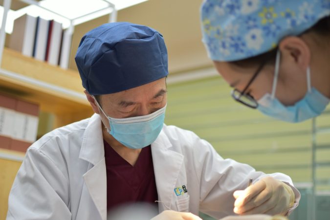 A Chinese doctor standing over a patient