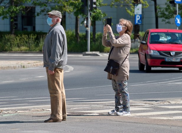 couple walking with masks on their phones.