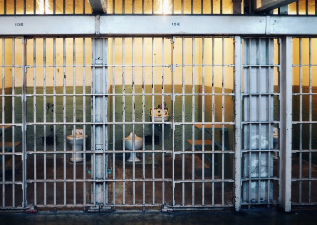 Prison cell with a sink and toilet behind bars