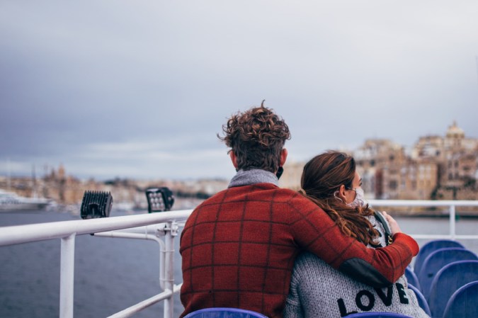 Couple in COVID-19 masks hugging on boat