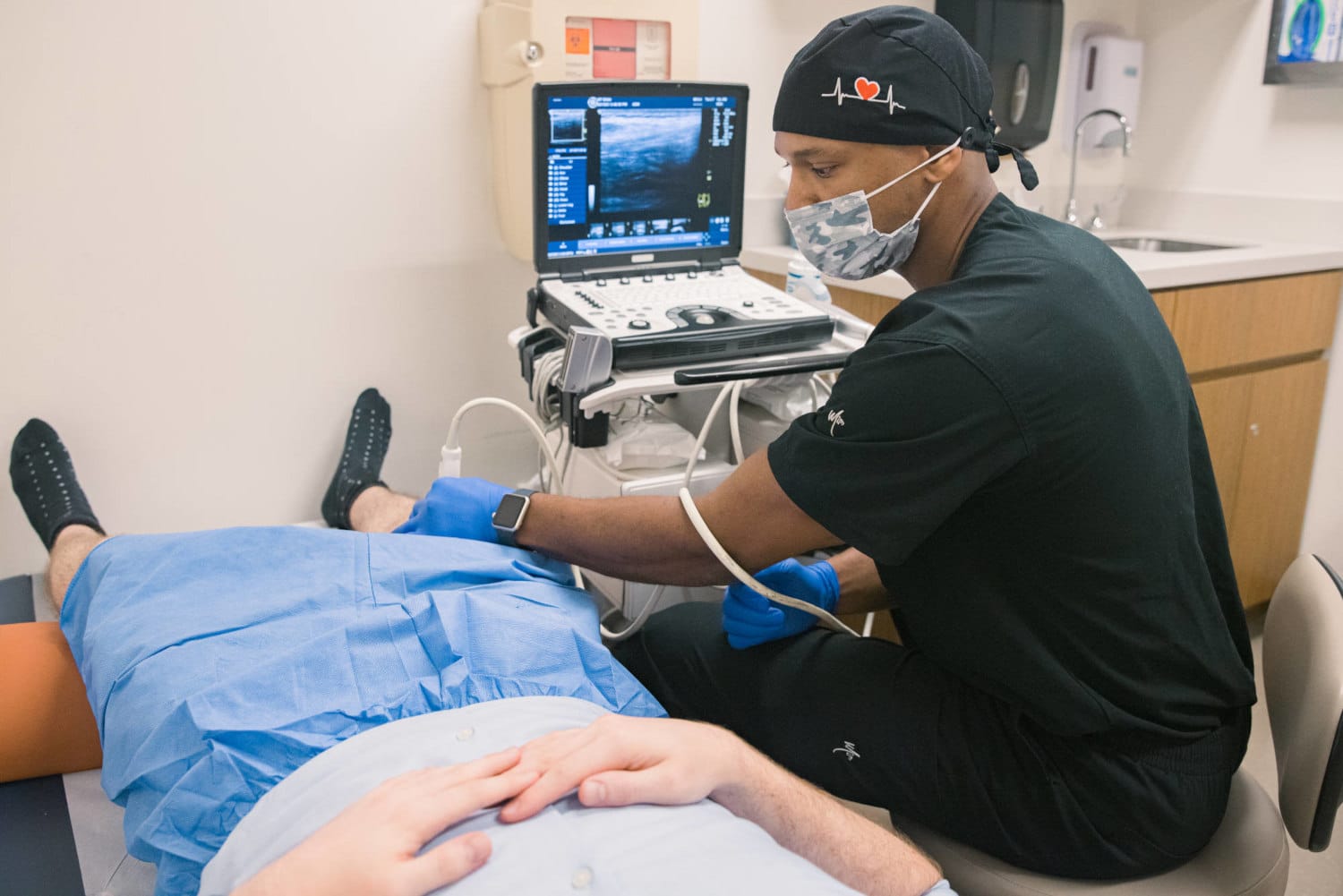 Doctor Aaron Bolds with a patient in a blue gown at a hospital scanning machine