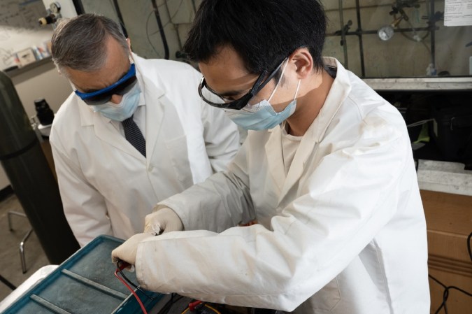 Two chemists pulling apart an old computer in a rare earth metal recycling experiment