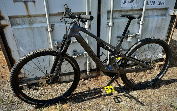Canyon Neuron ONfly CF 7 electric mountain bike leaning against a storage container