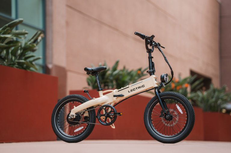 A white XP Lite 2.0 folding bike in front of red planters