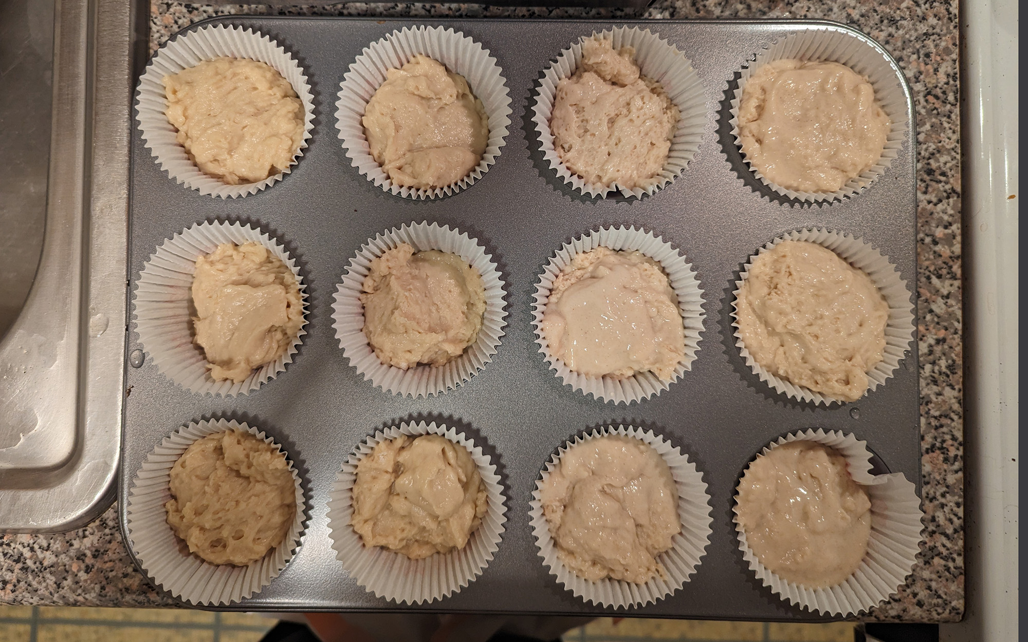 muffin tray on kitchen counter with uncooked batter