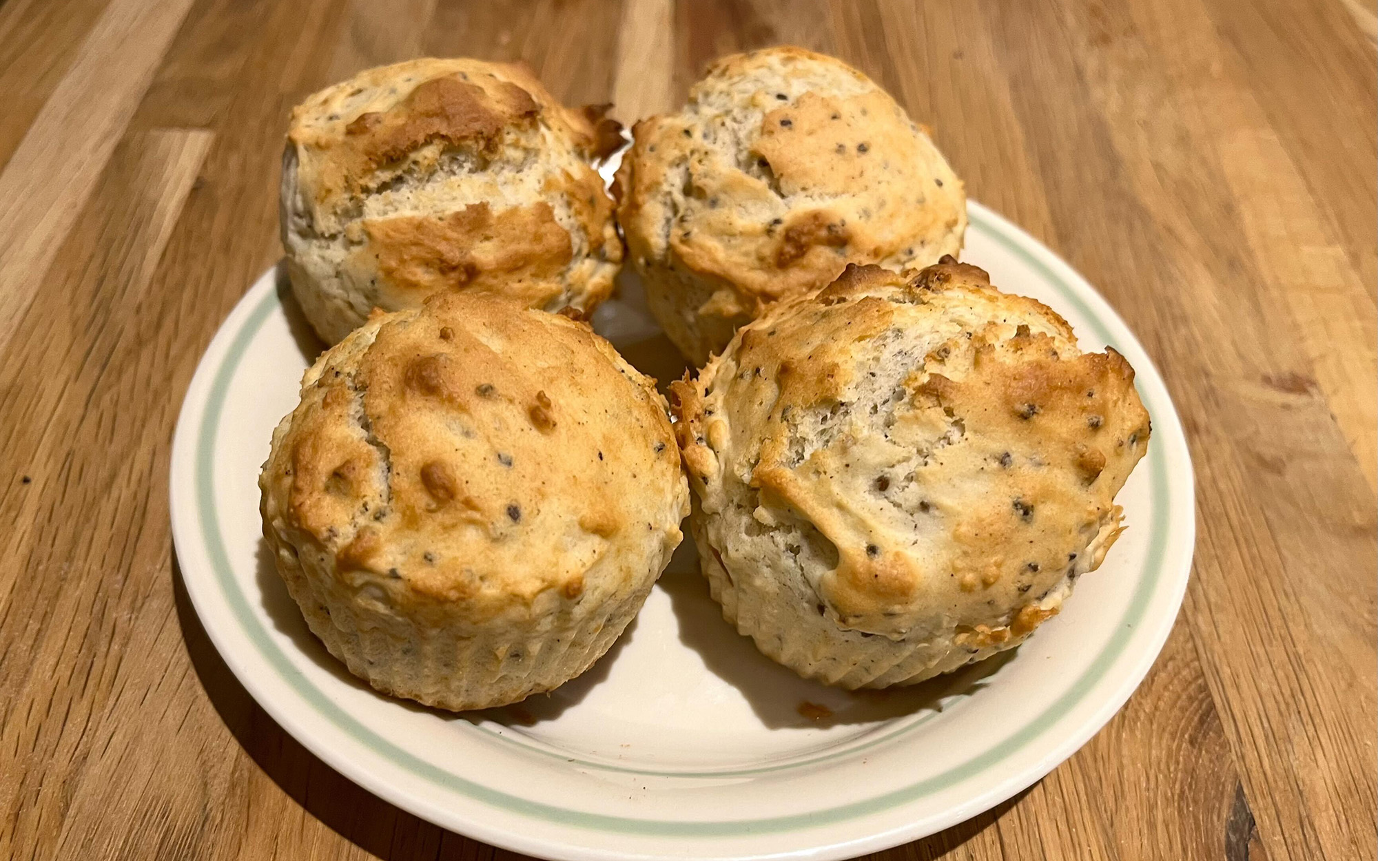 plate with four muffins sitting on a wooden kitchen counter