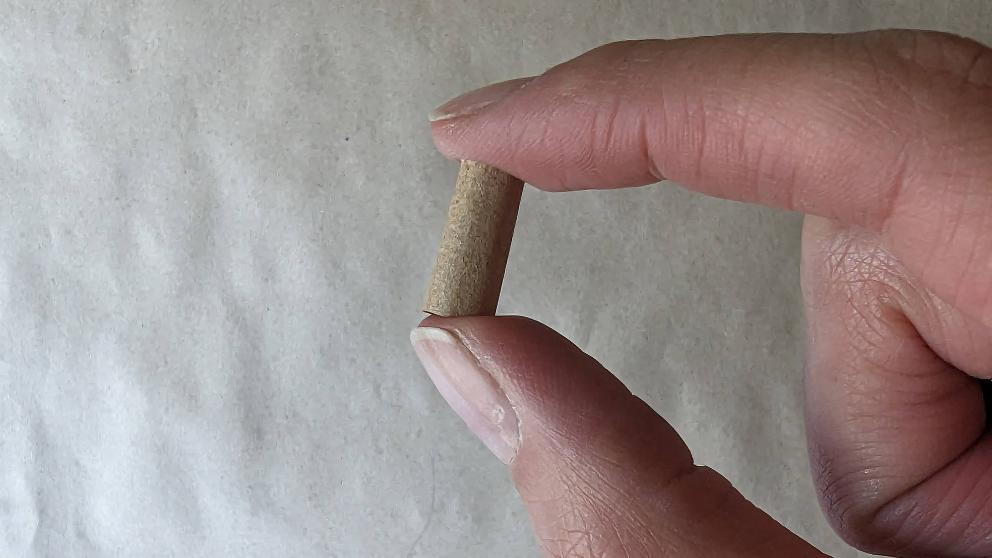 Hands holding a cardboard tip for smoking. 