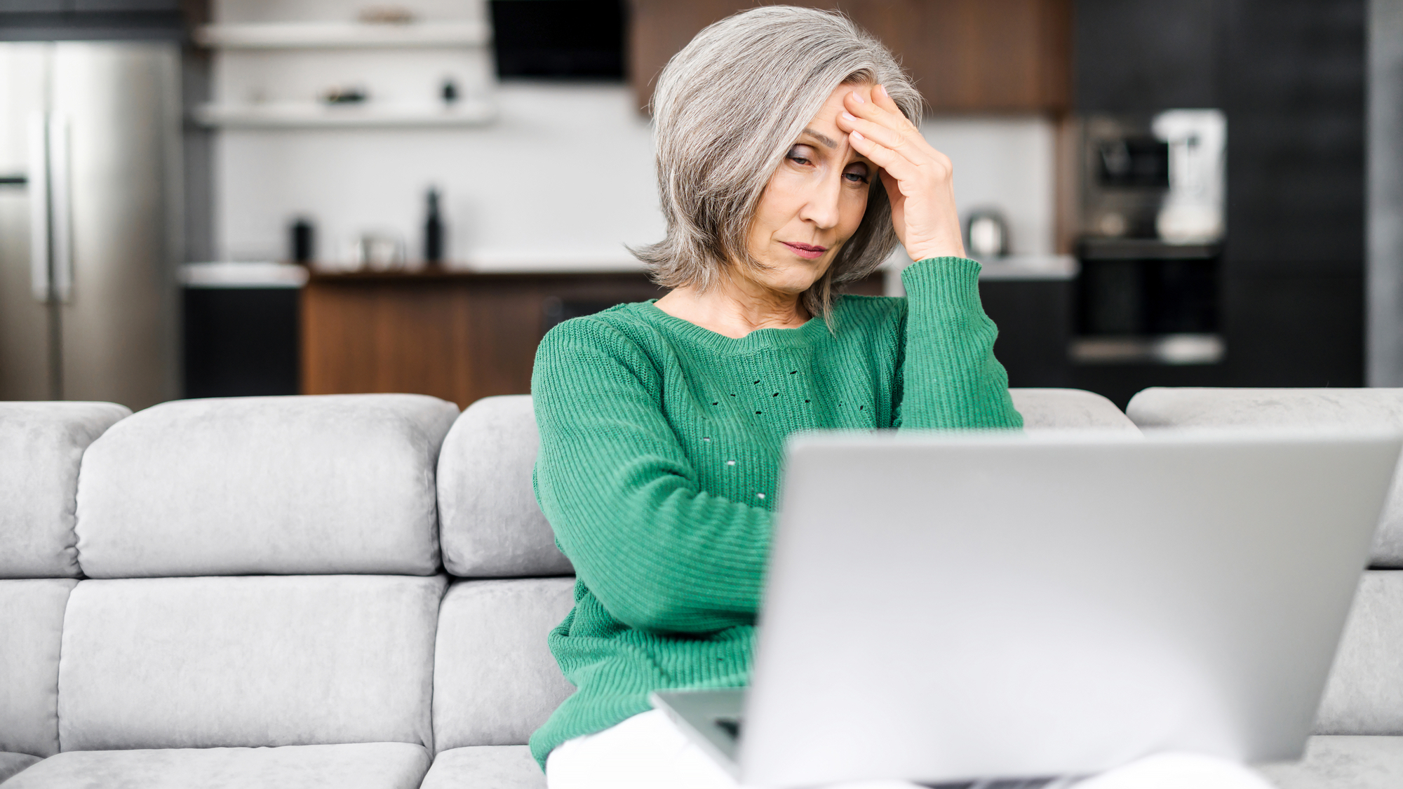 Upset senior woman looks at the laptop screen