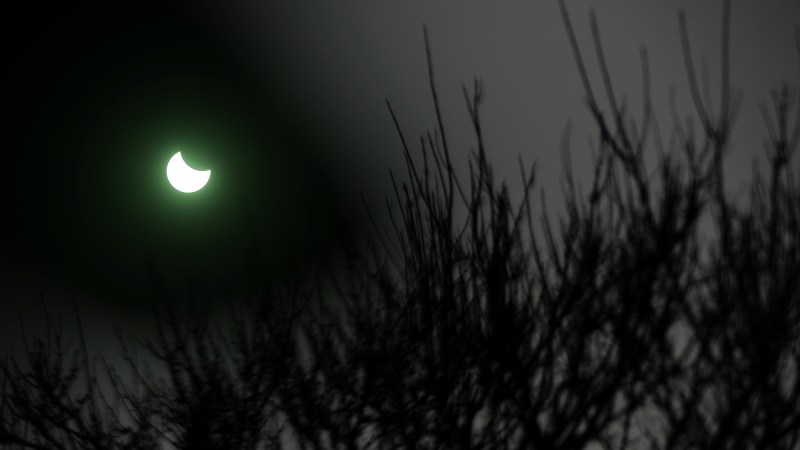 A man uses a tinted glass to watch as the moon passes infront of the Earth's star marking a total eclipse, the only one this year, in Vigo, northwestern Spain on March 20, 2015.