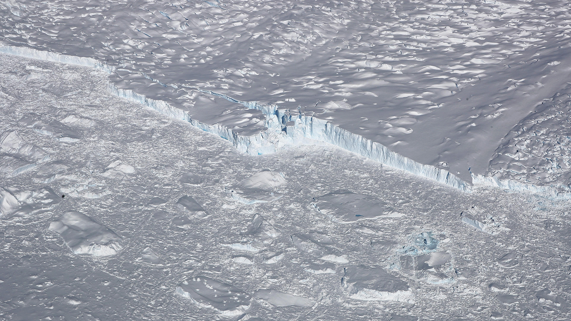 UNSPECIFIED, ANTARCTICA - OCTOBER 31: A calving glacier is seen from NASA's Operation IceBridge research aircraft, in the Antarctic Peninsula region, on October 31, 2017, above Antarctica. NASA's Operation IceBridge has been studying how polar ice has evolved over the past nine years and is currently flying a set of nine-hour research flights over West Antarctica to monitor ice loss aboard a retrofitted 1966 Lockheed P-3 aircraft. According to NASA, the current mission targets 'sea ice in the Bellingshausen and Weddell seas and glaciers in the Antarctic Peninsula and along the English and Bryan Coasts.' Researchers have used the IceBridge data to observe that the West Antarctic Ice Sheet may be in a state of irreversible decline directly contributing to rising sea levels. The National Climate Assessment, a study produced every 4 years by scientists from 13 federal agencies of the U.S. government, released a stark report November 2 stating that global temperature rise over the past 115 years has been primarily caused by 'human activities, especially emissions of greenhouse gases'. (Photo by Mario Tama/Getty Images)
