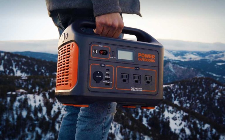 A person holdling a Jackery solar generator while standing outdoors.